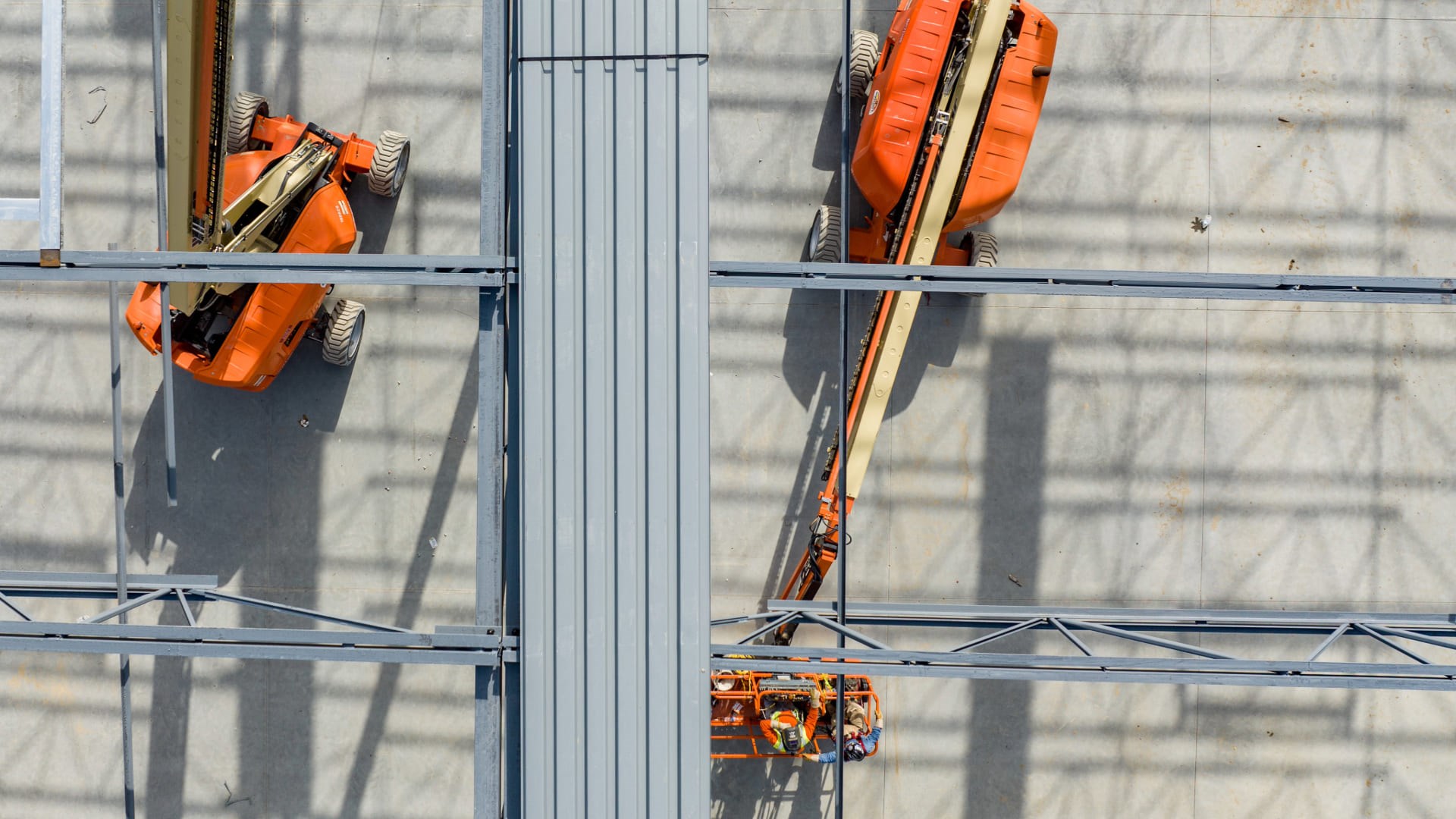 Vue aérienne de deux nacelles élévatrices utilisées sur un chantier, avec des travailleurs en hauteur, illustrant l’usage partagé des équipements.